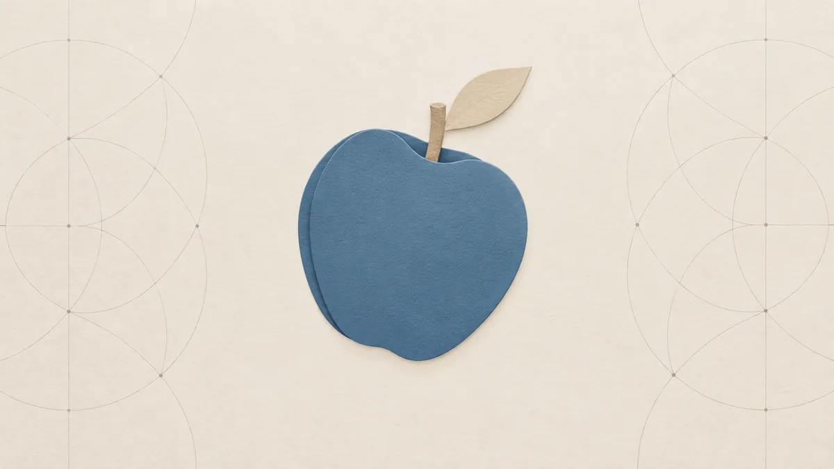 A slate-blue cut-paper apple with a short stem and one leaf, tipped in mid-fall, on warm off-white paper.