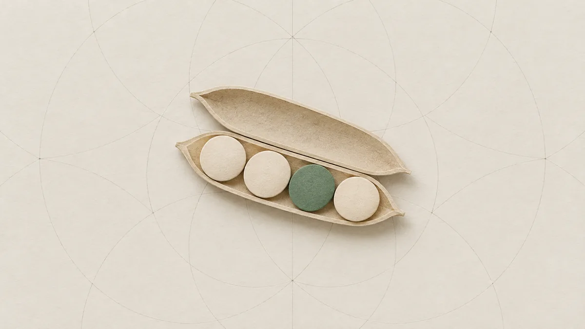 A cut-paper pea pod lying open with four peas in a row, three cream and one green, on warm off-white paper.