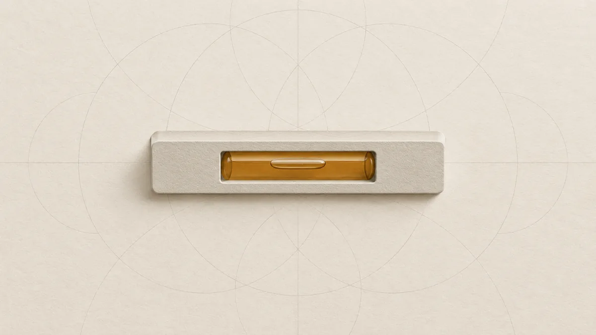 A cut-paper builder's level lying flat, its amber vial holding one bubble at the centre, on warm off-white paper.